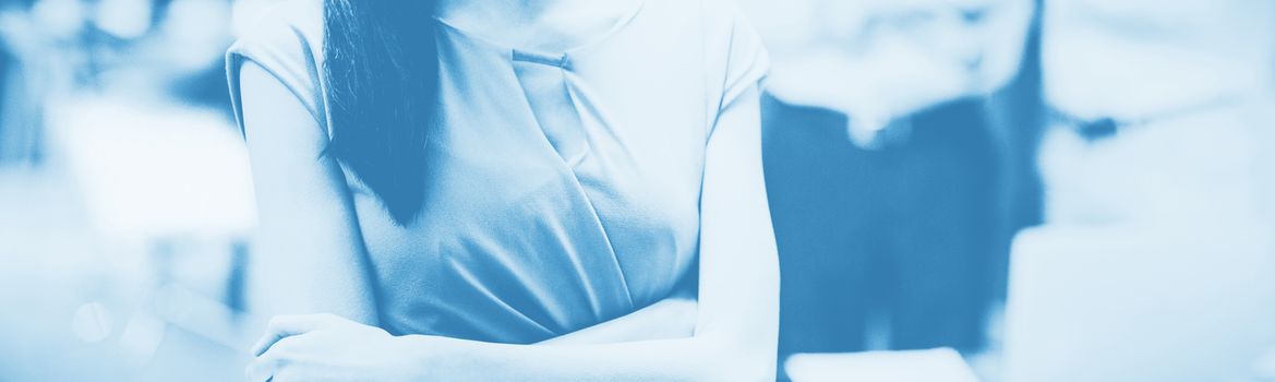 Portrait of happy businesswoman standing with arms crossed in office