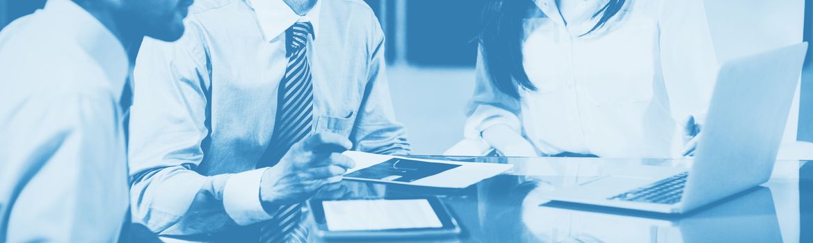 Businesswoman discussing with colleagues over laptop in office