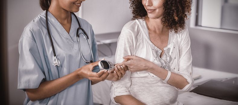 Doctor examining pregnant womans blood sugar in hospital