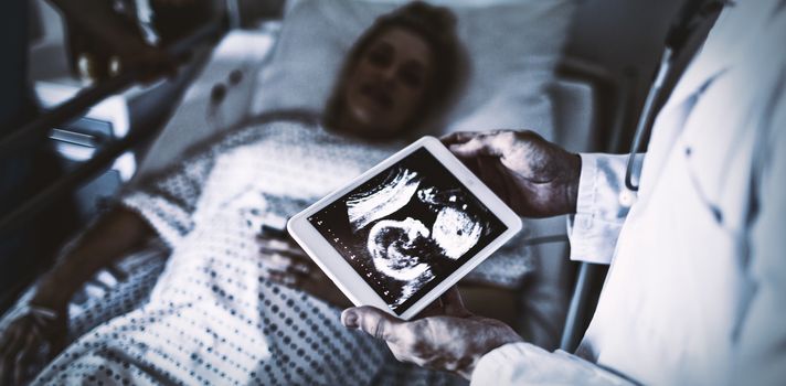 Male doctor looking at sonography report on a digital tablet in the hospital