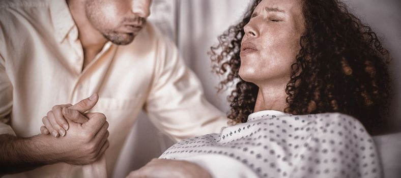 Man comforting pregnant woman during labor in ward of hospital