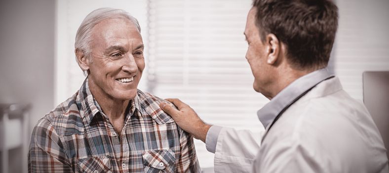 Doctor consoling senior man in clinic