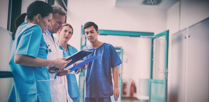 Doctor and surgeons discussing with report in corridor at hospital