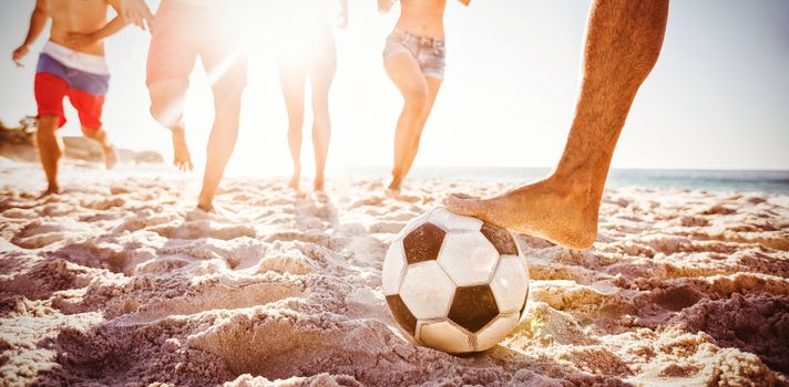 Friends playing football at beach