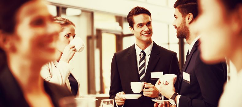 Businesspeople interacting with each other while having coffee in office