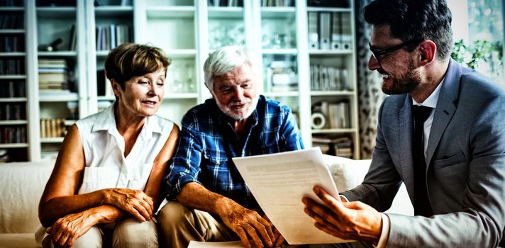 Senior couple planning their investments with financial advisor in living room