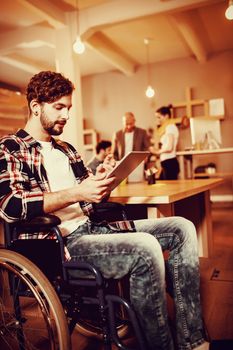 Graphic designer using digital tablet while colleagues interacting in background