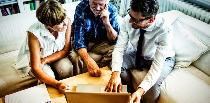 Senior couple planning their investments with financial advisor in living room