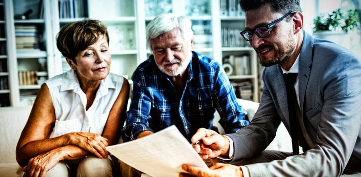 Senior couple planning their investments with financial advisor in living room