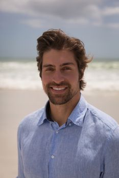 Portrait of happy man standing on the beach in front of the sea