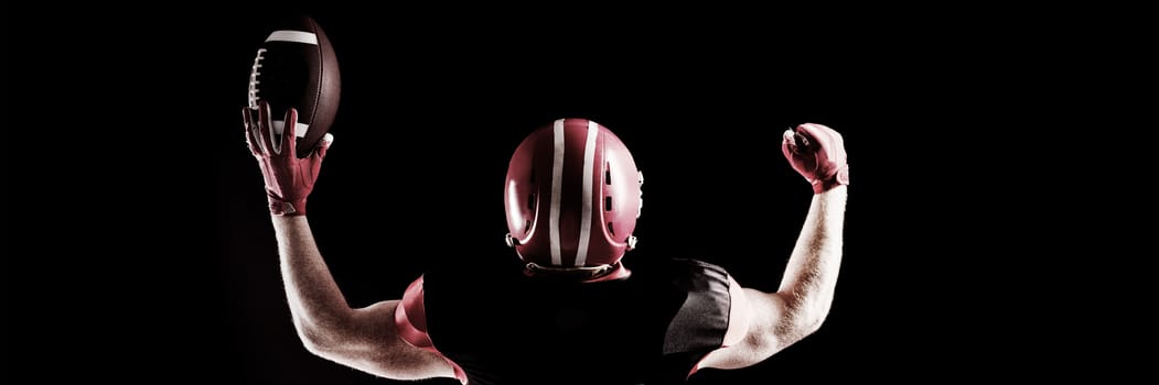 Excited American football player in helmet holding rugby ball
