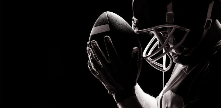 Close-up of American football player standing with rugby helmet and ball