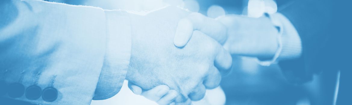 Close-up of businessman shaking hands with colleague in office