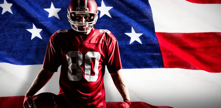 American football player standing with rugby ball against close-up of an american flag