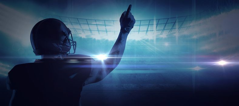American football player in helmet pointing upwards against american football arena