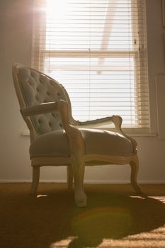 Low-angle view of a luxury modern armchair placed in front of a sunny window at home