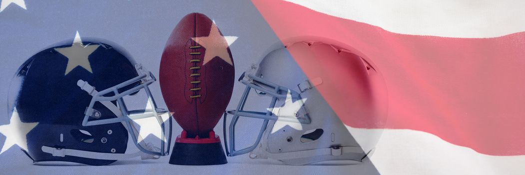 Close up of American football on tee by sports helmets against close-up of an american flag