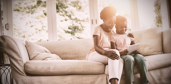 Mother and daughter using digital tablet at home