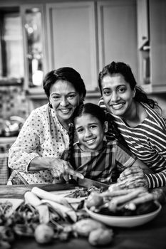 Portrait of smiling multi-generation family preparing food together in kitchen at home