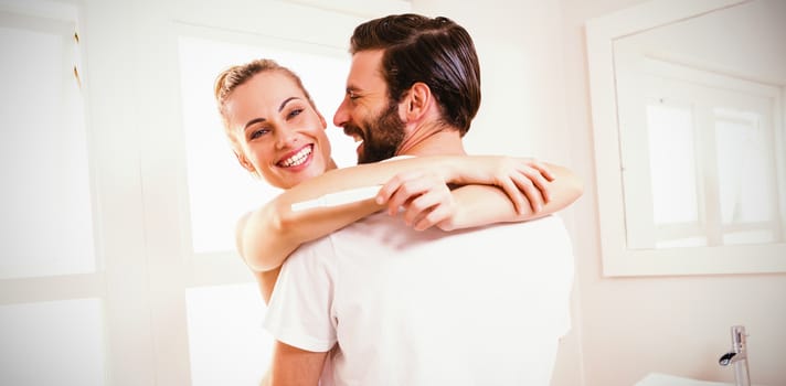Woman holding pregnancy test while embracing man at home