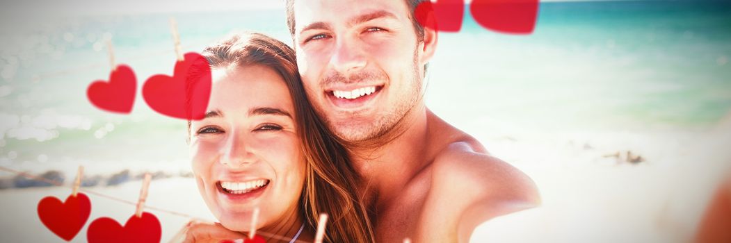 Hearts hanging on a line against couple taking a selfie