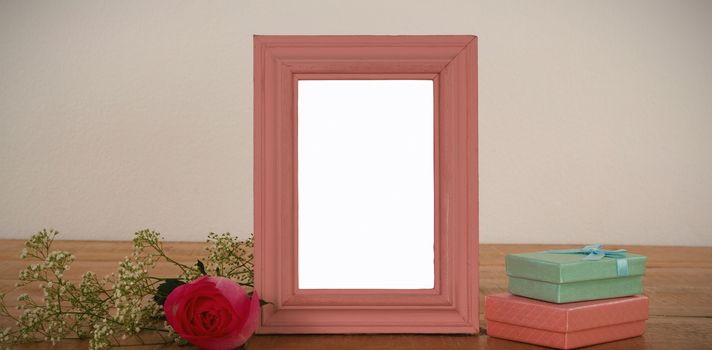 Empty photo frame, rose flower and gift boxes on a table