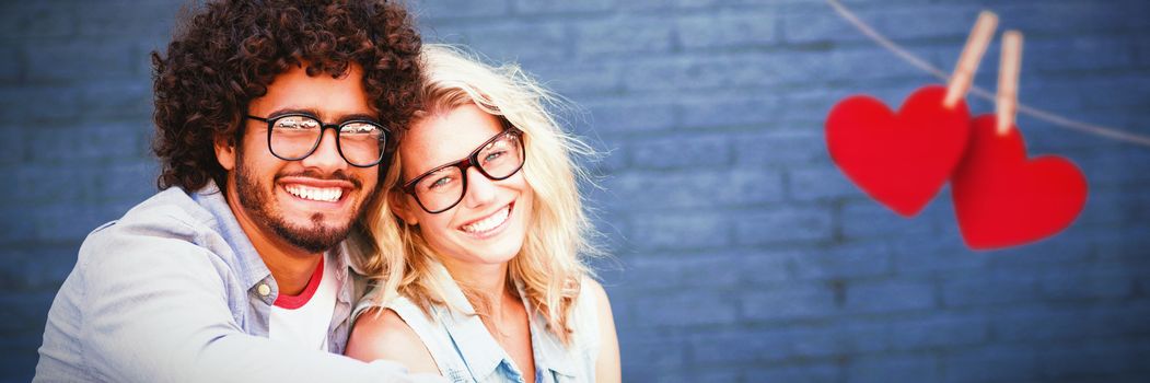 Hearts hanging on a line against portrait of young couple in spectacles