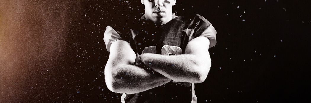 Splashing of powder against american football player standing with arms crossed