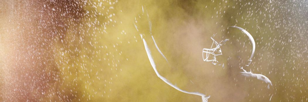 Splashing of dust powder against american football player in helmet pointing upwards