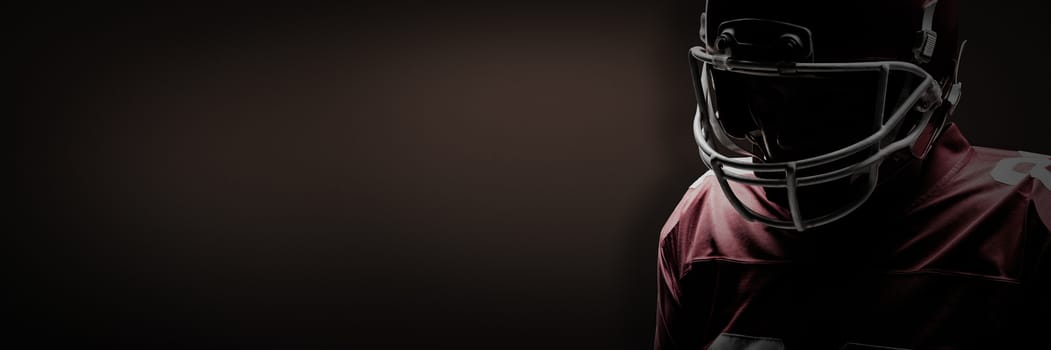 American football player standing in rugby helmet against dark brown background