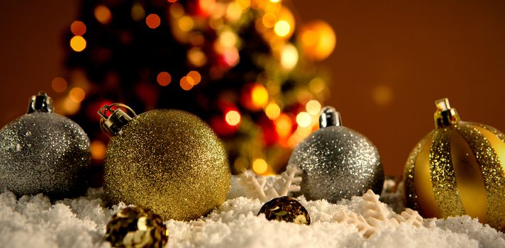 Christmas balls lying in the snow against white carpet against unfocused decoration