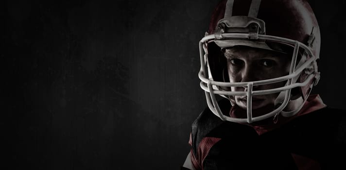 American football player standing with rugby helmet against full frame shot of grunged concrete wall