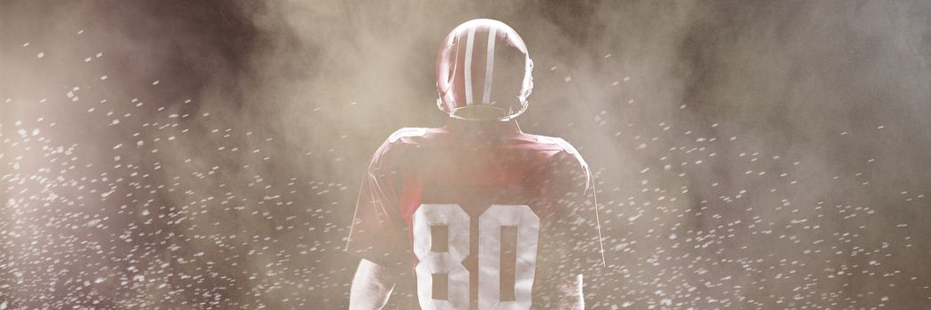 Splashing of dust powder against american football player standing with rugby helmet