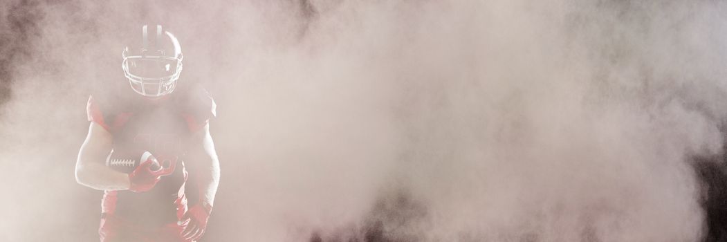 Splashing of color powder against american football player in helmet taking position against black background