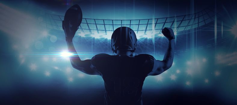 American football player standing with helmet holding football in victory against american football arena