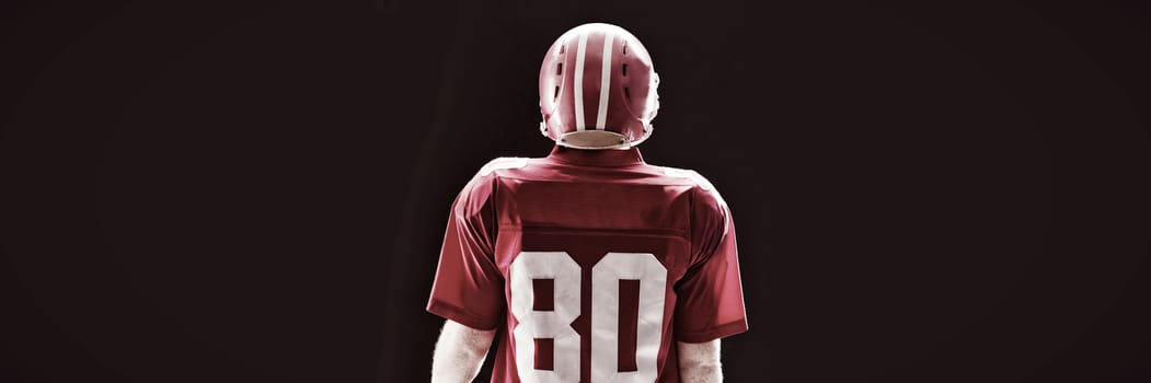 Rear view of American football player standing with rugby helmet