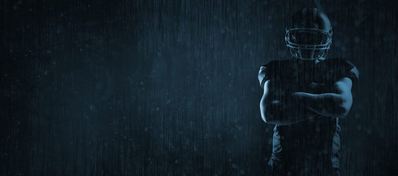 American football player standing with arms crossed against old weathered wall