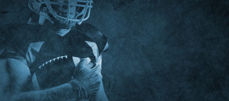 American football player in helmet standing with rugby ball against full frame shot of patterned white wall