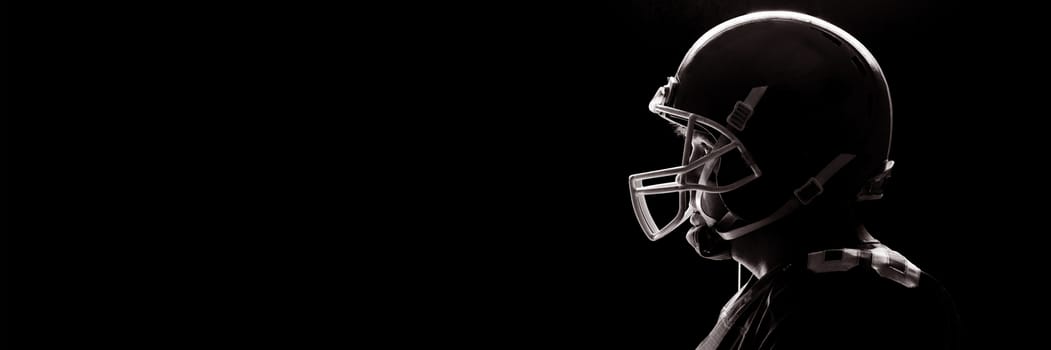 Side view of American football player standing with rugby helmat