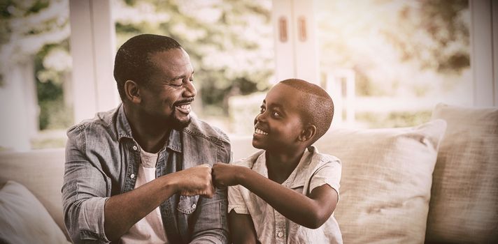 Father and son fist bumping while playing video game at home