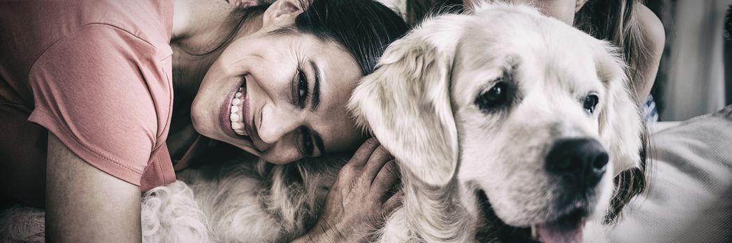 Mother and daughter with dog sitting in living room at home