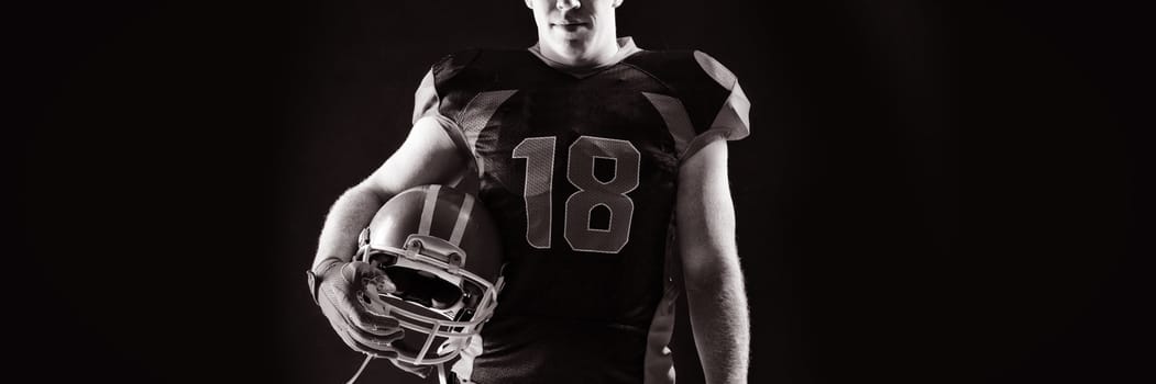 Young American football player standing with helmet
