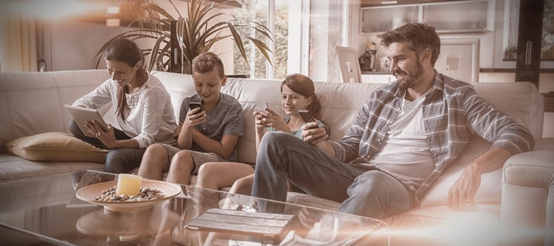 Family using digital tablet and mobile phone in living room at home