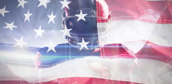 American football player in helmet holding rugby ball against full frame of american flag