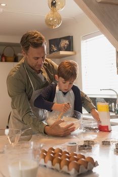 Front view of loving father with his son preparing cookies in kitchen at home 