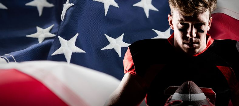 American football player holding rugby ball against full frame of american flag