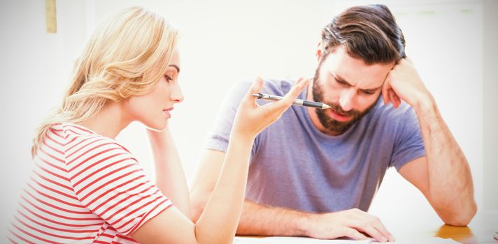 Worried young couple checking on bills at home