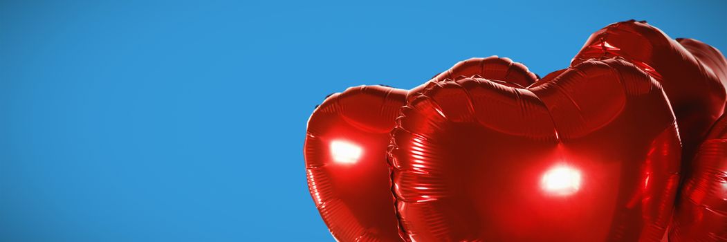 Red heart shape balloons against blue background