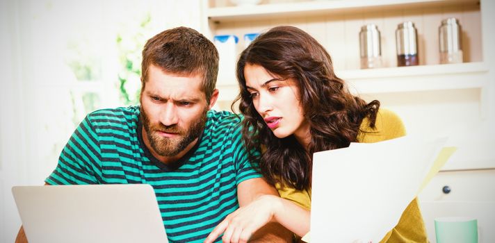 Couple paying their bills with laptop in kitchen at home