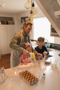 Front view of loving father with his children preparing food in kitchen at home